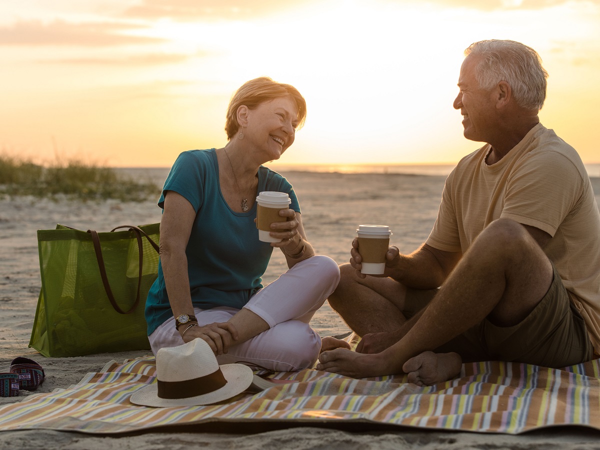 Senior couple having coffee picnic break on a beach vacation.